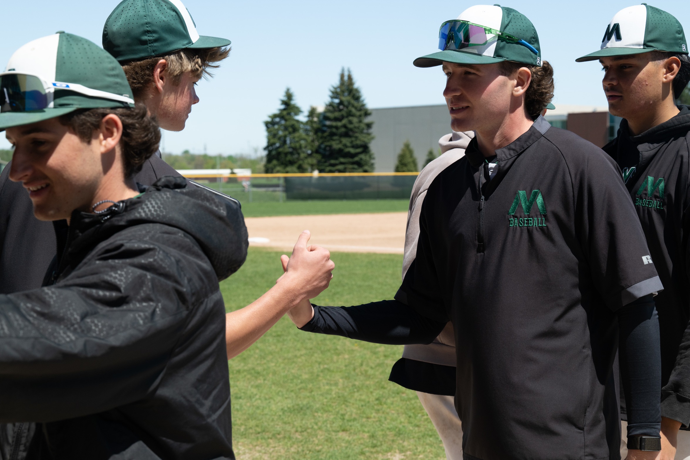 Baseball teammates high five and fist bump each other.