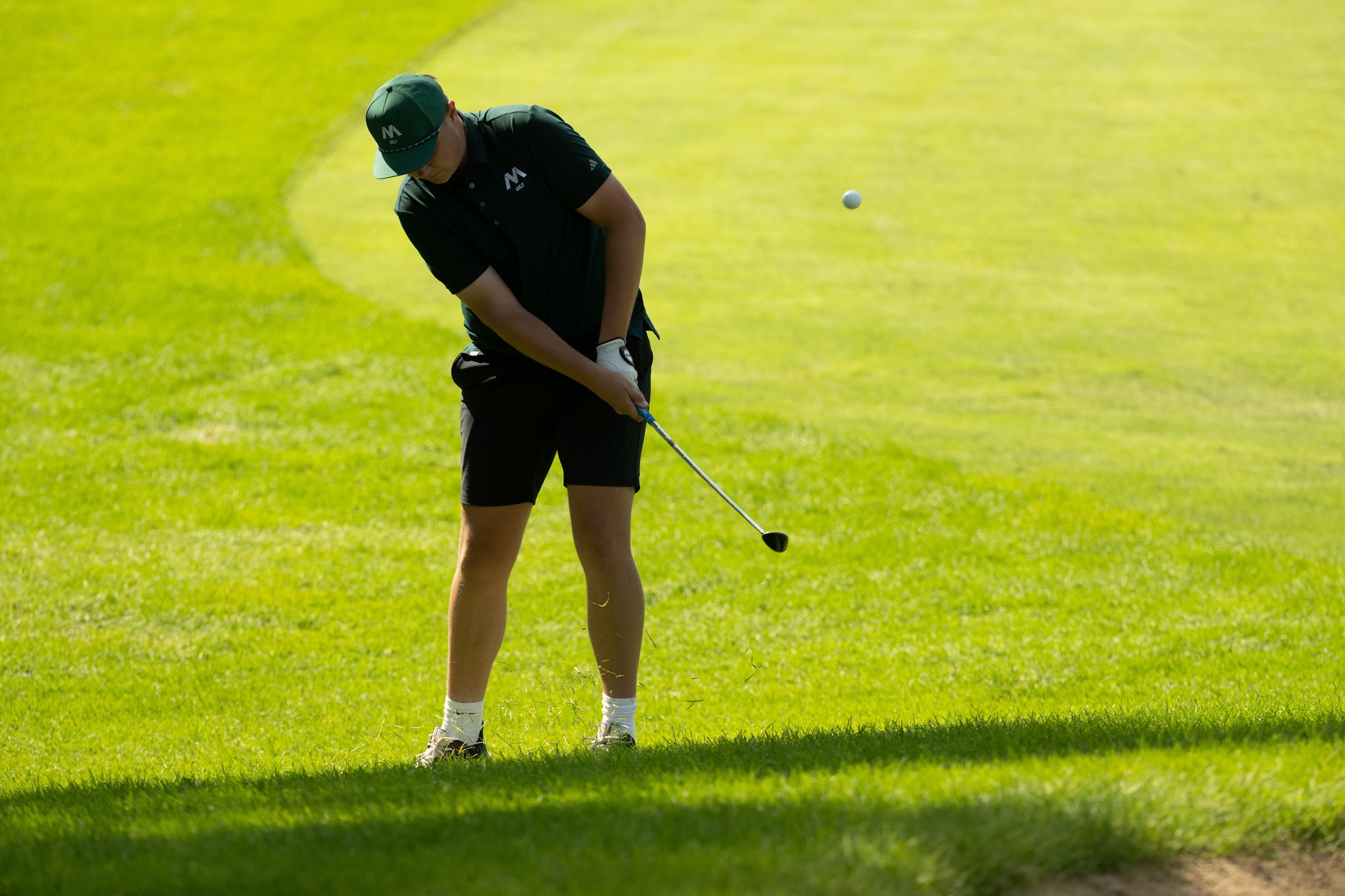 A golfer hits a ball.