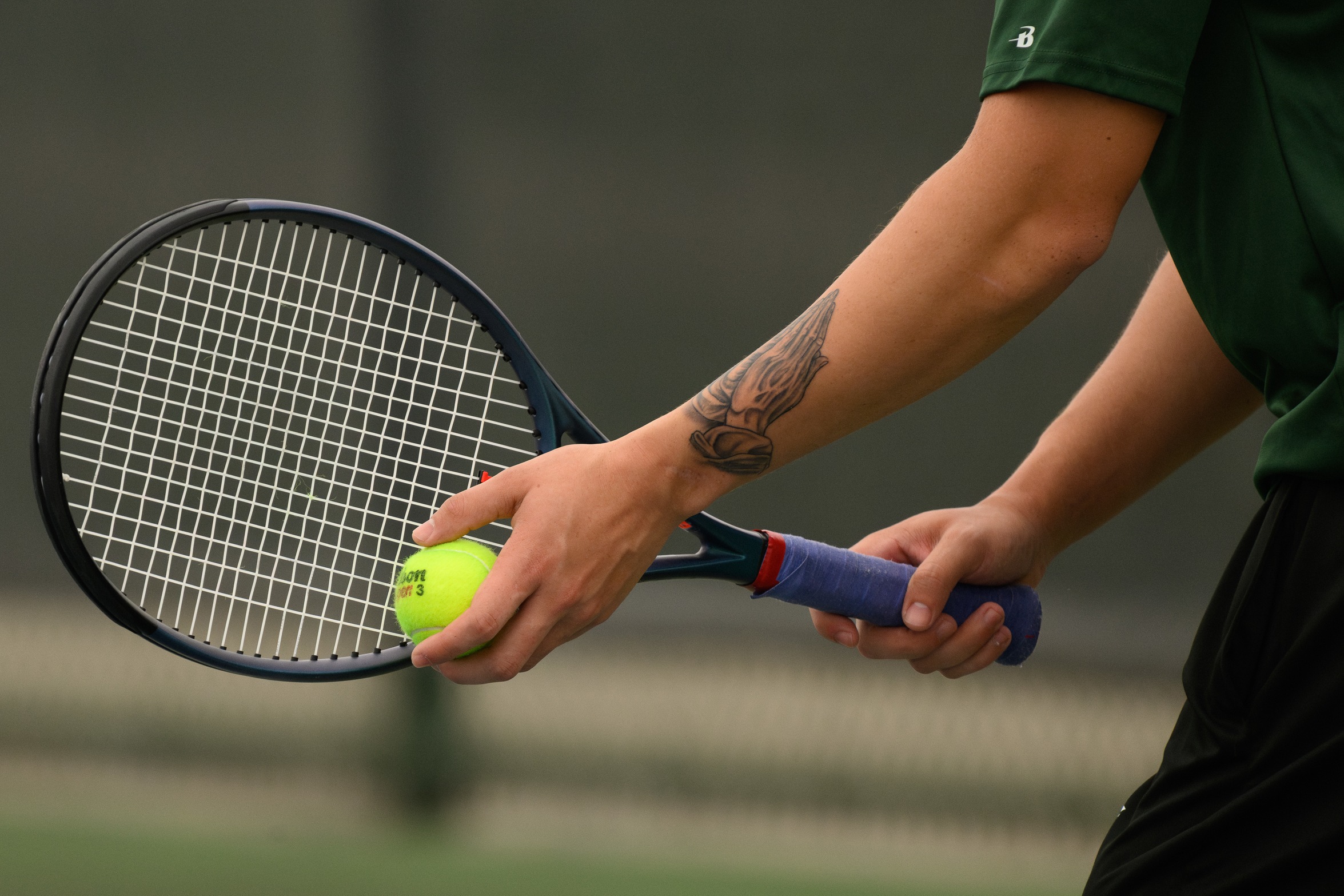 A tennis player's hands with a racquet and a ball.