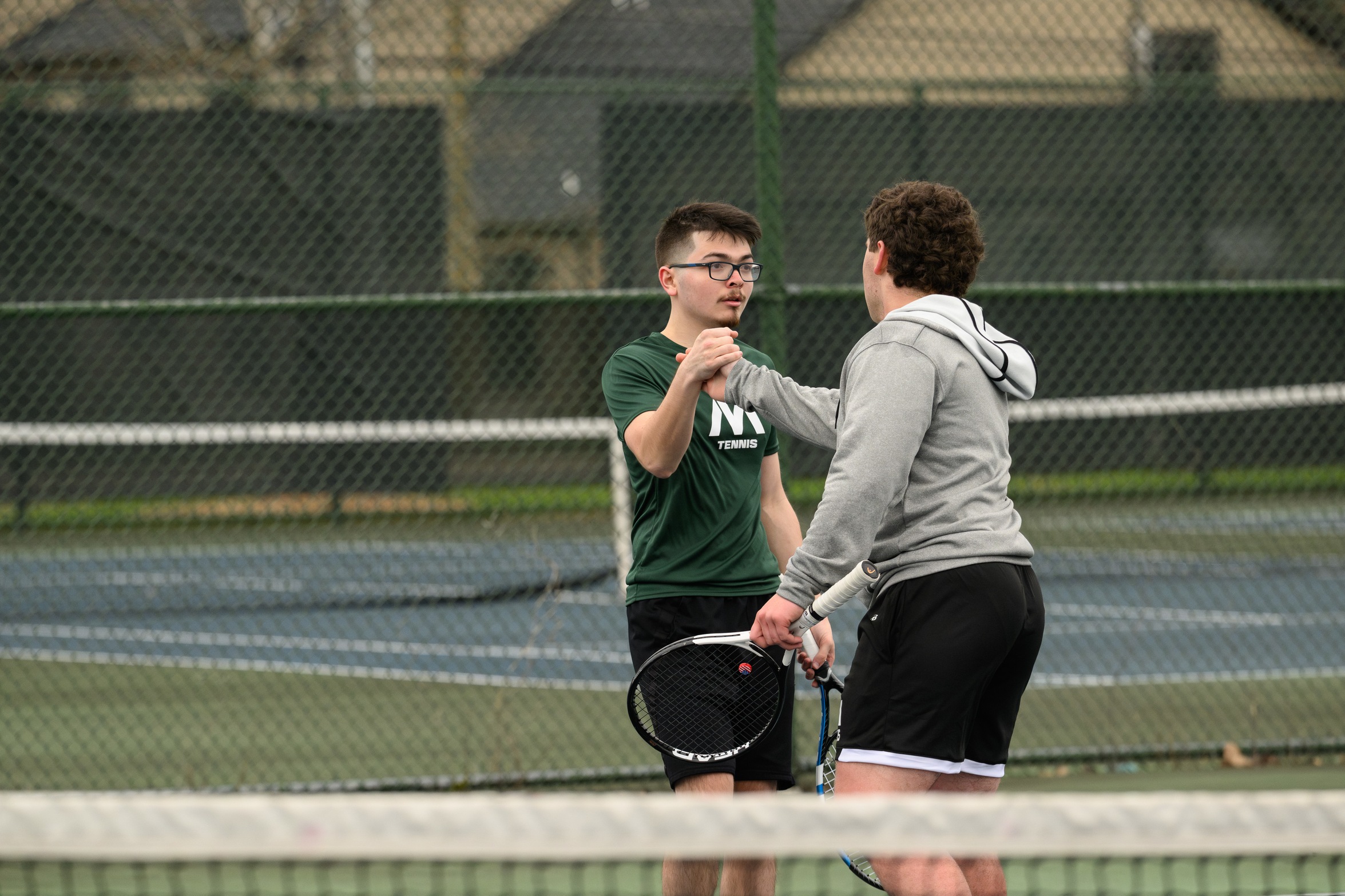 Two Moraine Valley men's tennis players high five each other.